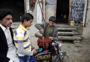 A boy fills the tank of a motorbike with smuggled petrol along a roadside shop in Quetta