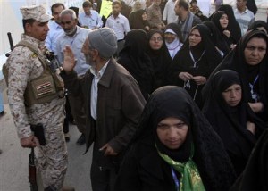 Iranian Shi'ite Muslim pilgrims walk past a member of Iraq's security personnel in Kerbala