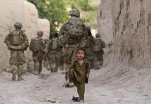 A boy plays on a street as U.S. Army soldiers of 82nd Airborne Division, patrol during a mission in Zahri district of Kandahar province
