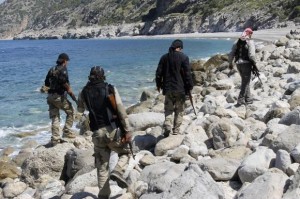 Rebel fighters walk with their weapons at the beach in Latakia province near the town of Kasab