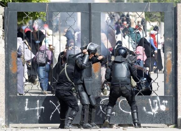 Riot police attempt to break open the entrance of the al-Azhar University Campus during clashes in Cairo