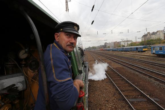 A train engineer looks out of a historic steam locomotive as it pulls a Tehran-bound train into Nyugati Terminus in Budapest