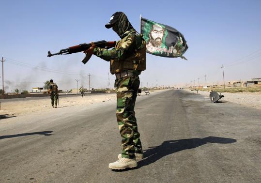 File photo of a fighter from the Shi'ite Badr Brigade militia wearing a religious flag as he guards a checkpoint outside the town of Amerli