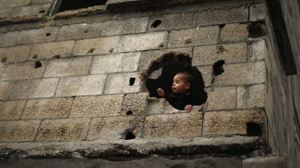 Palestinian boy looks out through a hole in his family house, that witnesses said was damaged by Israeli shelling during the July-August war between Israel and Hamas-led Gaza militants, in the east of Gaza City