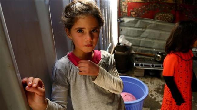 An Iraqi girl ,displaced by the violence of ISIL terrorists, looks at the camera as she stands in a shelter built for pilgrims but now housing internally displaced people (IDP) on January 5, 2015, in the city of Najaf.